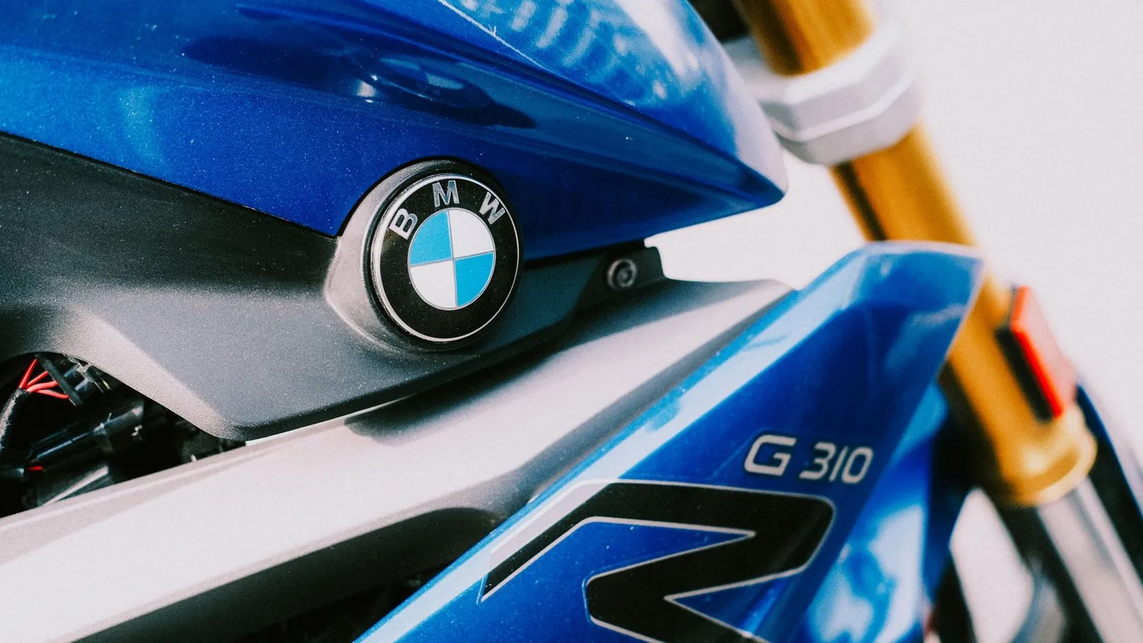 Une moto BMW trail grise stationnée sur une route de montagne, avec un pilote équipé prêt à partir